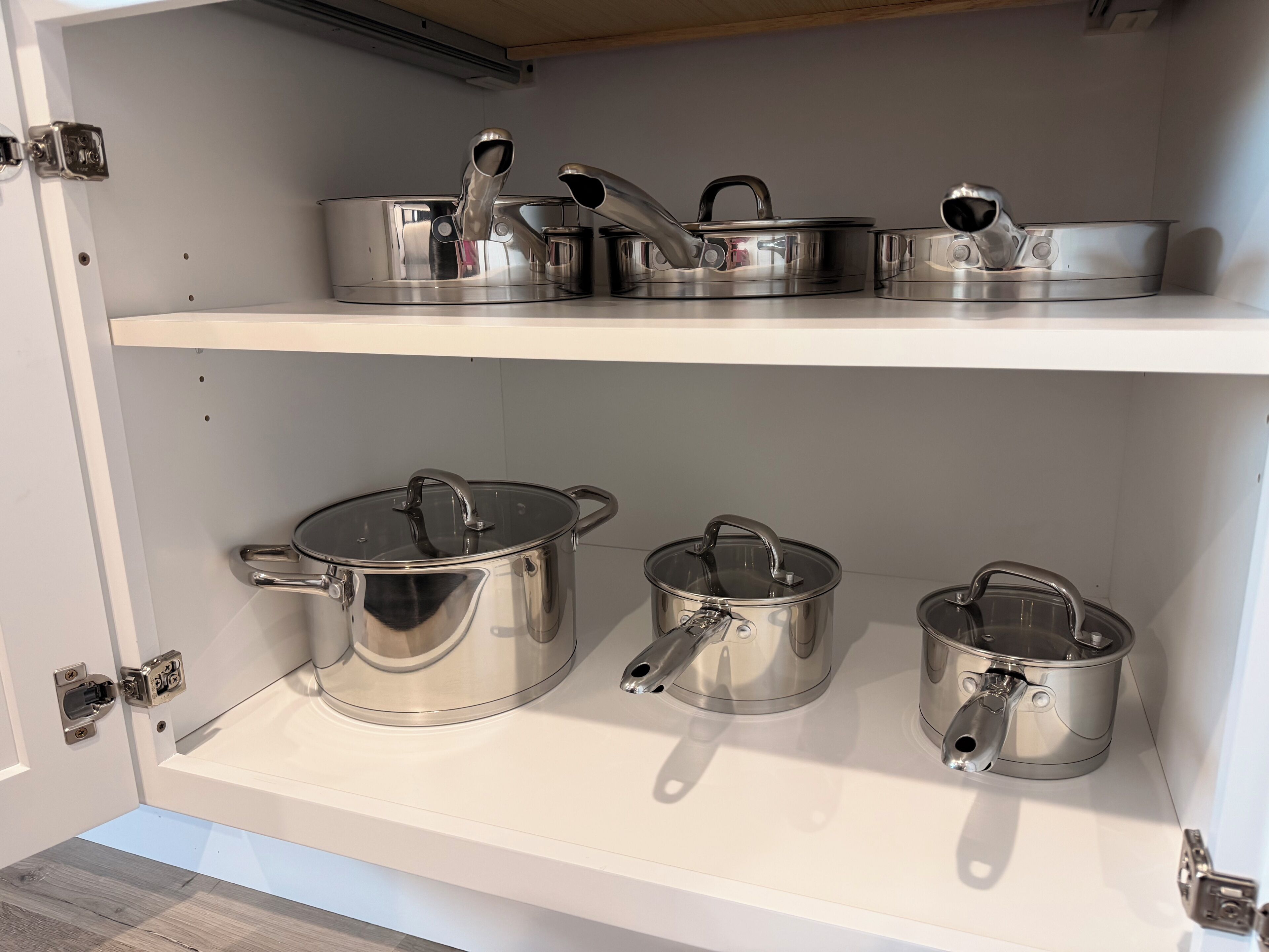 A kitchen with stainless steel cookware on shelves.
