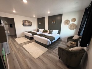 A modern bedroom with two beds, a sofa, and a small table. - CB&M Downtown Suites (Roosevelt)