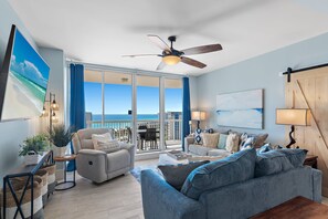 A spacious living room with a balcony, a ceiling fan, and a view of the ocean. - ☀️Gulf View-Private Beach-Beach Front Pool-Hot Tub-Spa-St Lucia 1202☀️ (Destin)