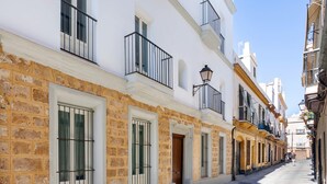 Una calle estrecha flanqueada por edificios con fachadas de piedra, balcones y ventanas con rejas de metal.