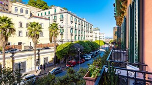 Vista de una calle con edificios, coches aparcados y palmeras.
