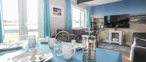 A dining area with a table set for four, a television mounted on the wall, and a scenic mural.