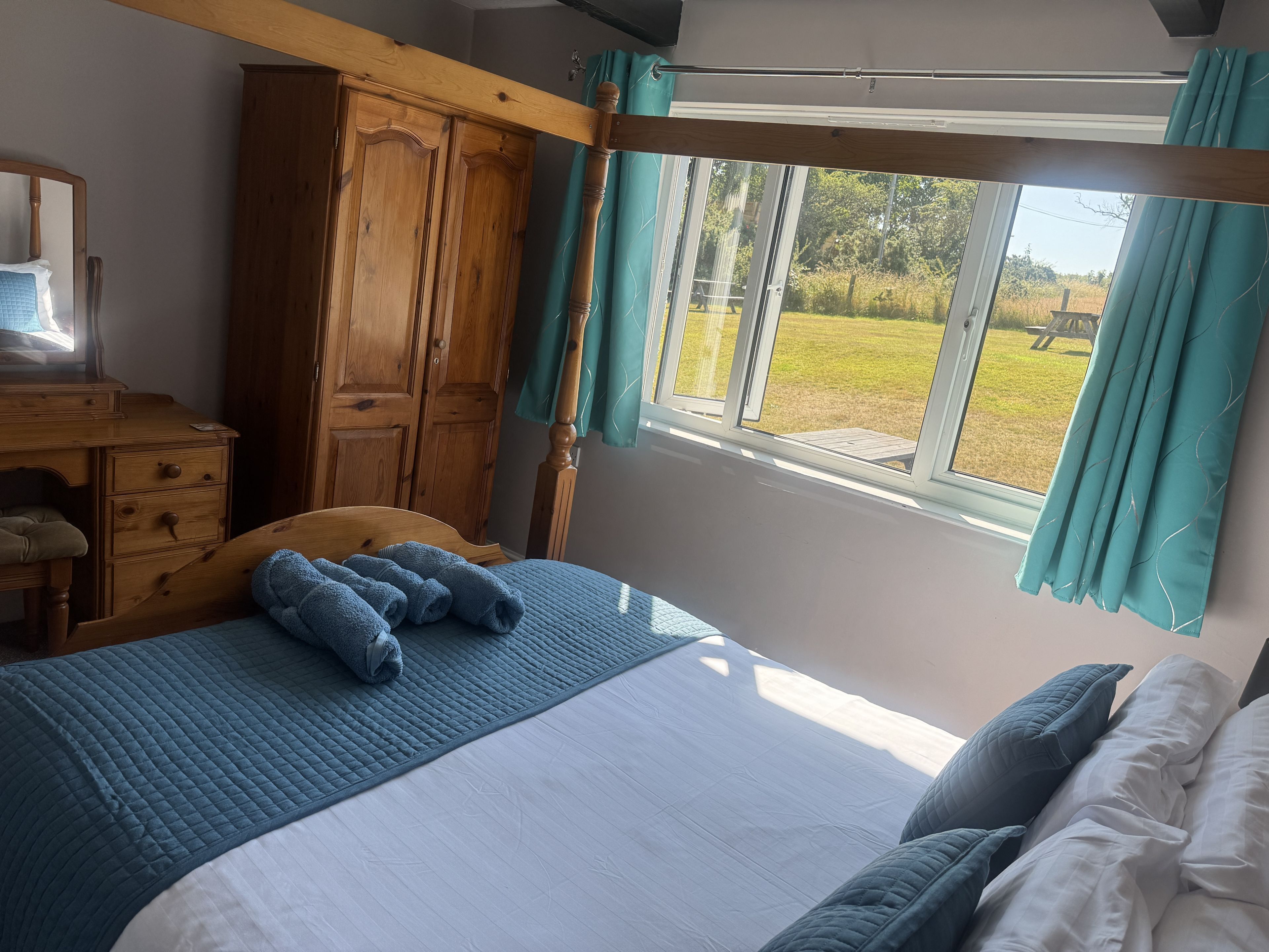 Ein Schlafzimmer mit einem Bett, einem Holzschrank und einem Fenster mit Vorhängen.