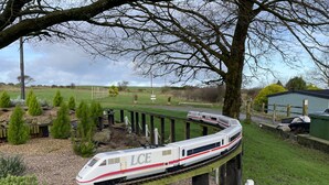 A model train on a track with a green building in the background.