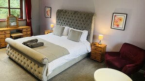 A neatly arranged bedroom with a large bed, bedside tables, a chair, and a dresser.