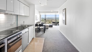 A modern kitchen with a dining area and a balcony with a city view. - Sierra Broadbeach - West Hinterland View (Broadbeach)