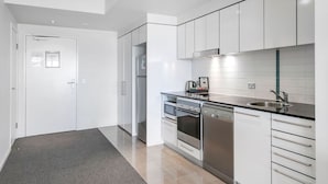 A modern kitchen with white cabinets, stainless steel appliances, and a black countertop. - Sierra Broadbeach - West Hinterland View (Broadbeach)