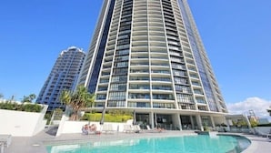 A high-rise hotel with a pool area, multiple balconies, and a clear blue sky. - Sierra Broadbeach - West Hinterland View (Broadbeach)