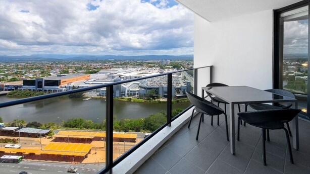 A balcony with a view of a river and cityscape, a table, and chairs. - Sierra Broadbeach - West Hinterland View (Broadbeach)