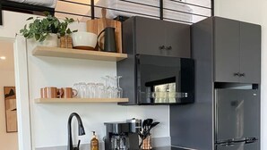 Une cuisine moderne avec des meubles gris, un évier en acier inoxydable et un four à micro-ondes encastré.