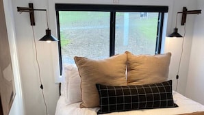 Une chambre avec un grand lit, deux lampes de chevet, une fenêtre donnant sur un beau paysage et un tapis sur le sol.