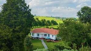 A house with a red roof, surrounded by lush greenery and a well-maintained lawn. - Farmhouse Retreat on 85-acre tea Estate - 2331 (Limuru)