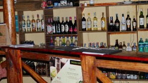 A bar area with shelves stocked with various liquor bottles. - Eco Deluxe Double at Tausa Tsavo Lodge - 2341 (Voi)