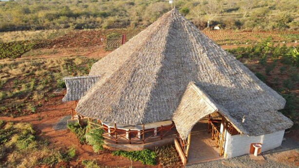 A thatched-roof structure with a circular layout, surrounded by a dry, bushy landscape. - Eco Deluxe Double at Tausa Tsavo Lodge - 2341 (Voi)