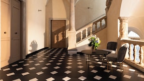 Una hall con pavimento a scacchi, una scala e un'area salotto con un tavolo e sedie.
