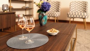 Un tavolo da pranzo con due bicchieri di vino, una ciotola di stuzzichini e un vaso con fiori.