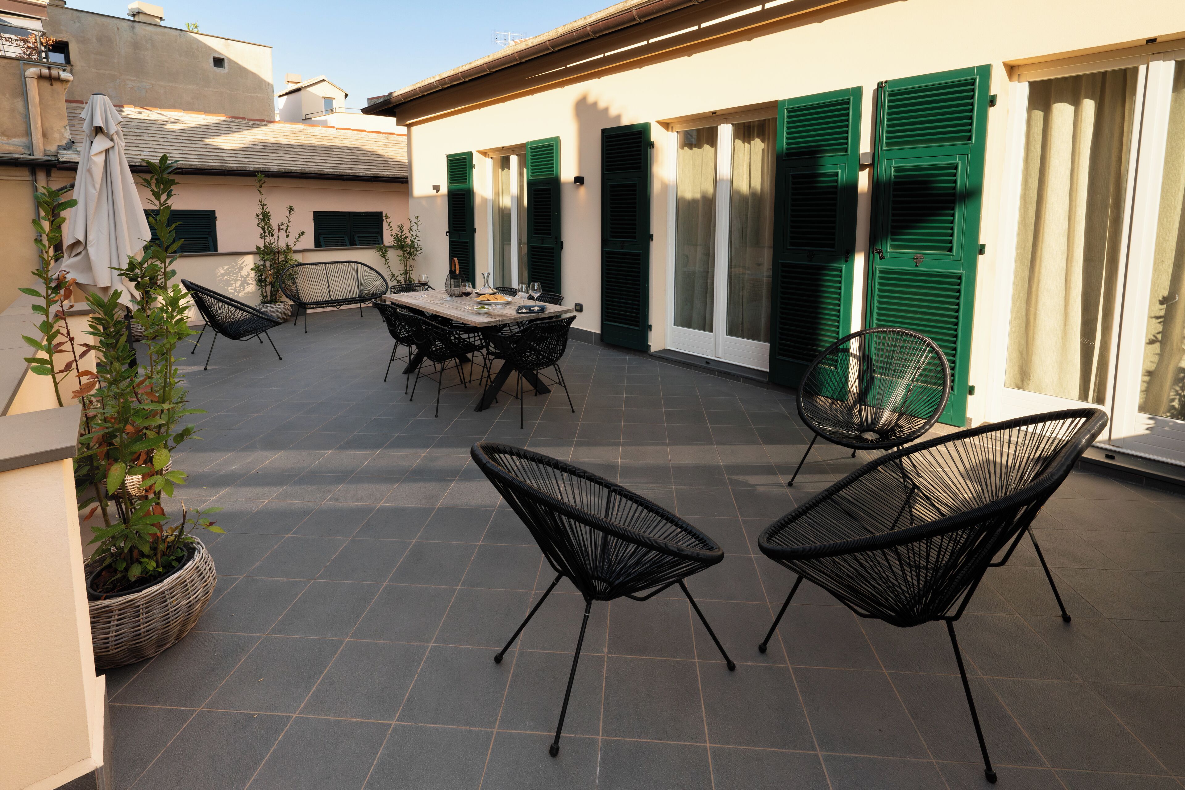 An outdoor patio with a table and chairs, potted plants, and a view of the building's exterior.