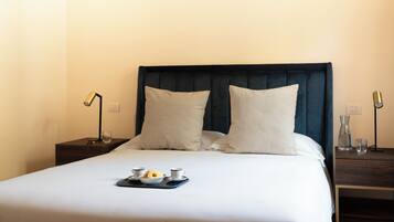 A neatly made bed with a tray of breakfast items, two bedside lamps, and a dark headboard in a hotel room.