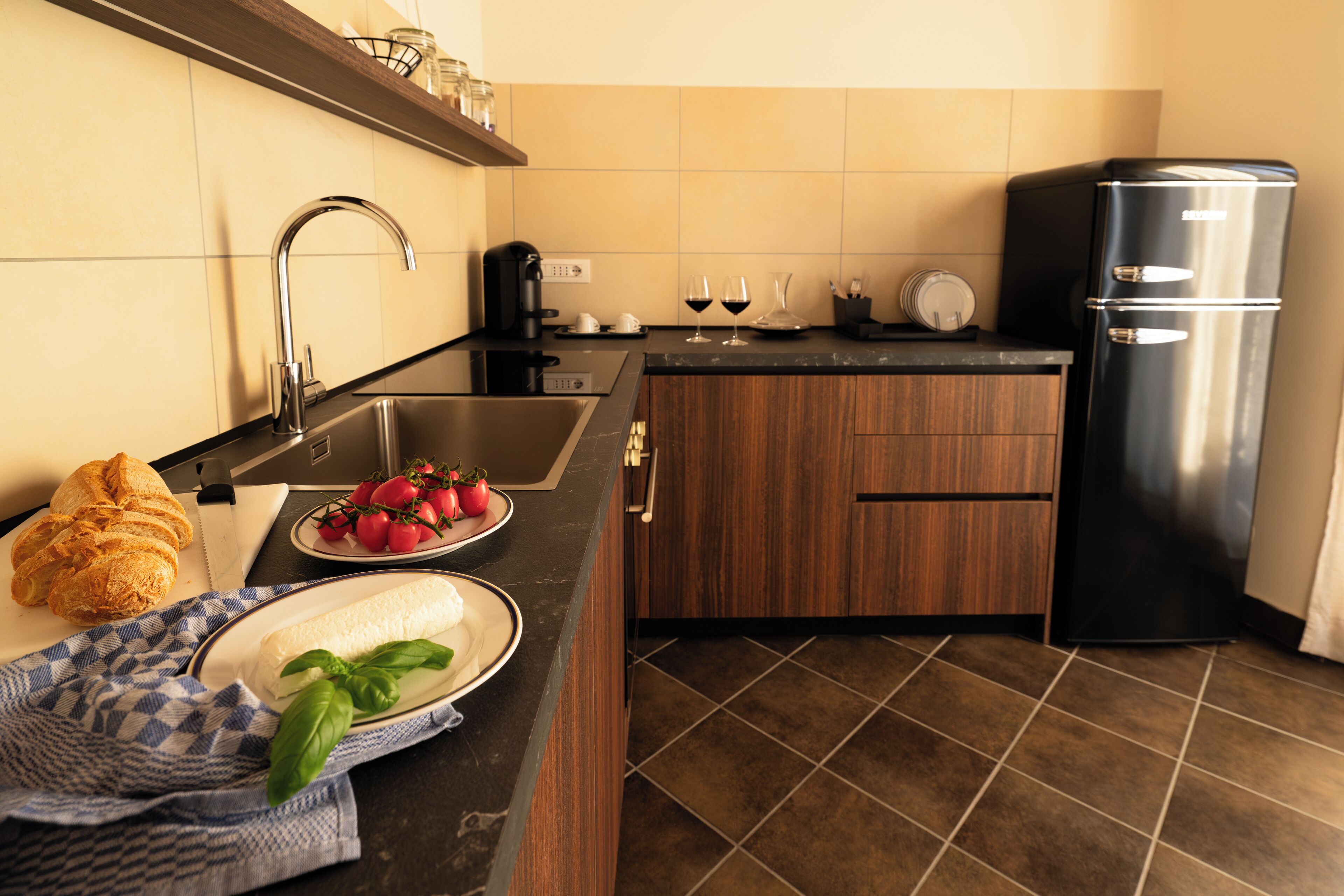A kitchen with a sink, a black refrigerator, and a countertop with food items.