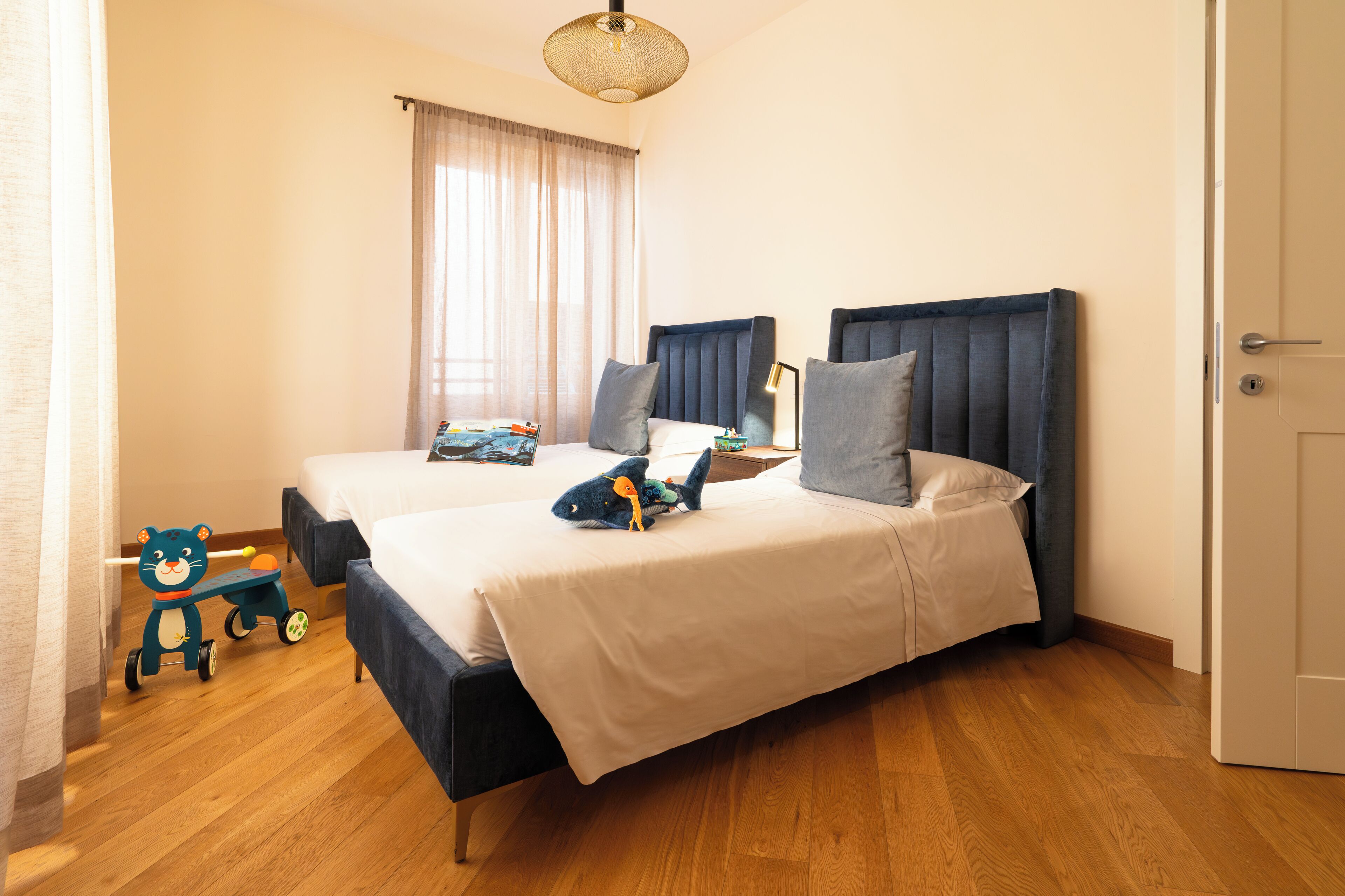 A double bed with a dark headboard, a bedside table with a lamp, and a window with curtains.