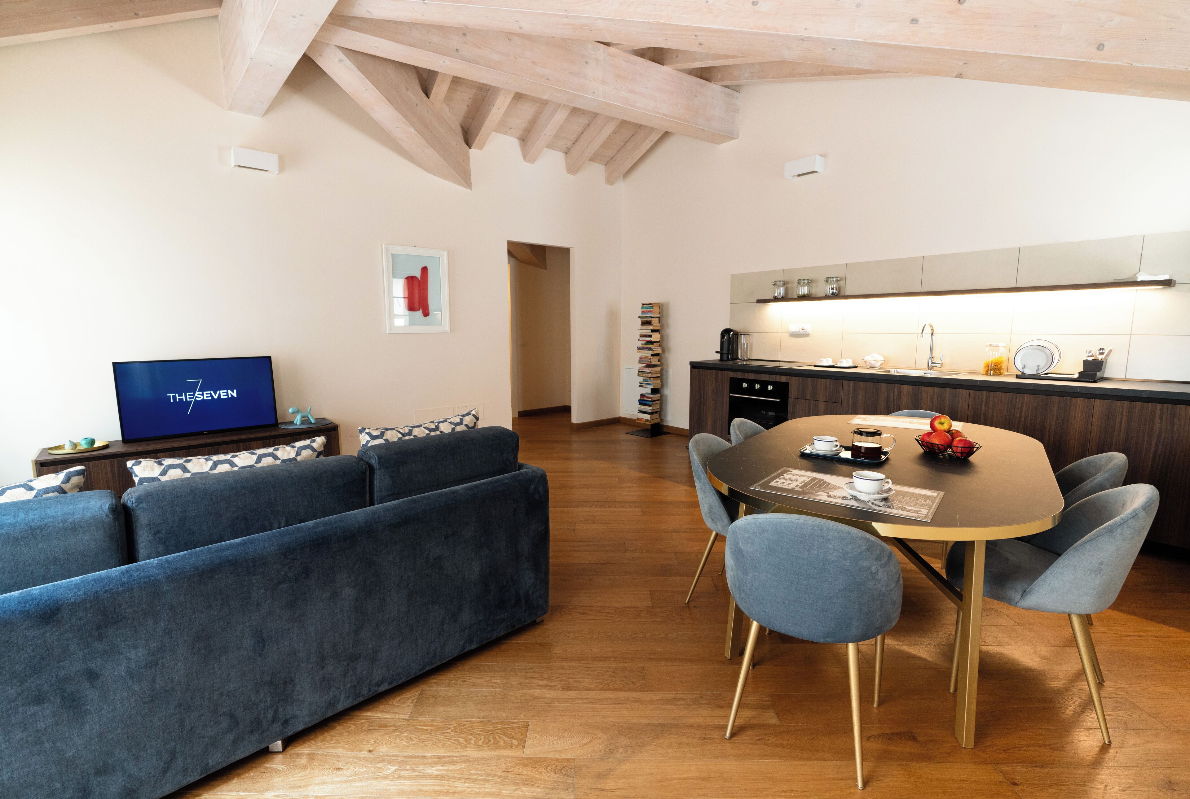 Un salon moderne comprenant un ensemble canapé, une table à manger avec des chaises et un coin cuisine avec un évier et un plan de travail.