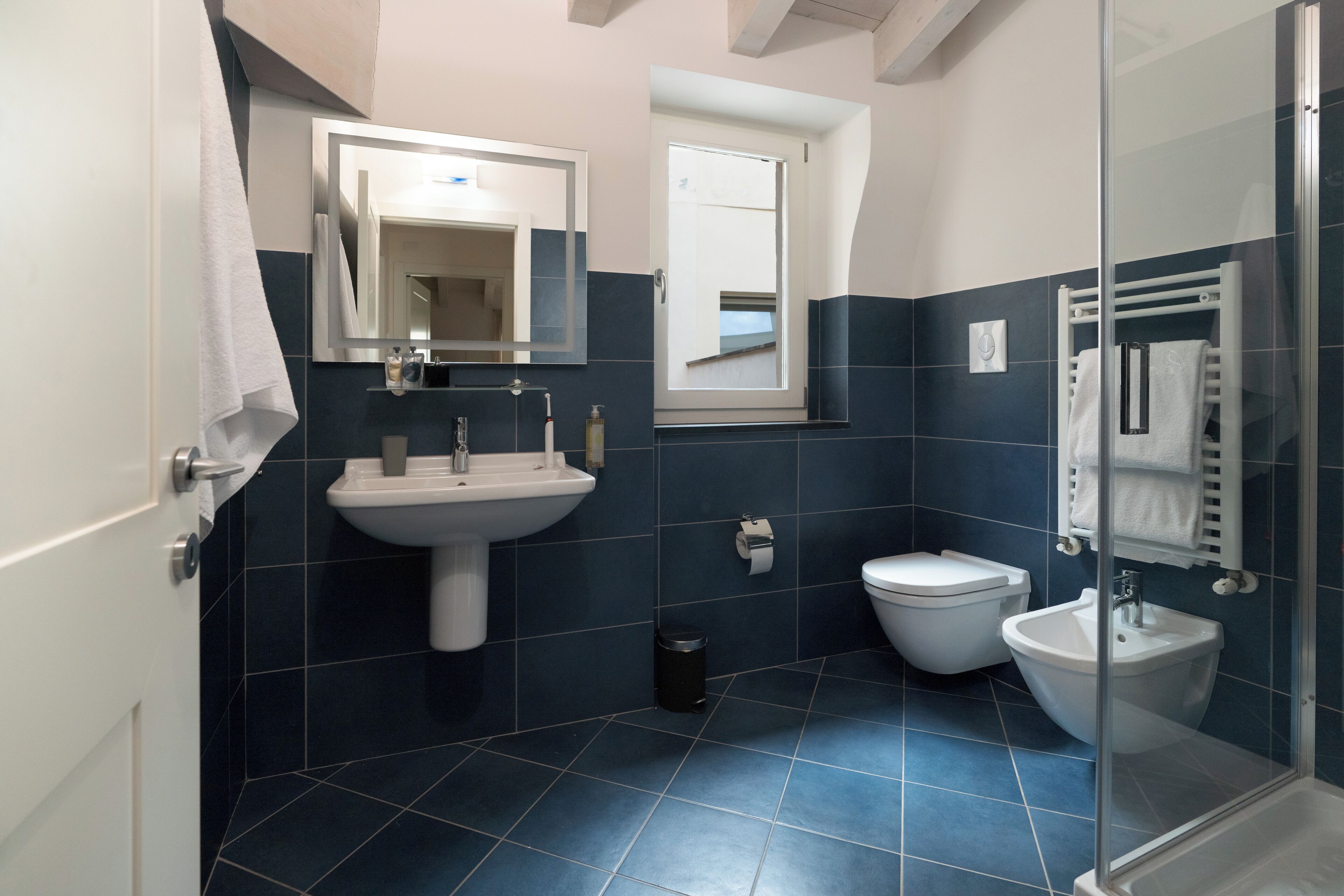 Een moderne badkamer met een wastafel, toilet, bidet en een douchecabine met glazen wanden.