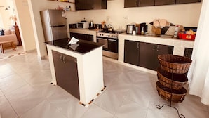 A modern kitchen with a central island, black cabinets, and a stove.