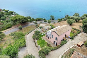 Une propriété située sur la côte, comprenant une maison de plain-pied, une allée pavée et un petit bateau amarré sur l’eau.