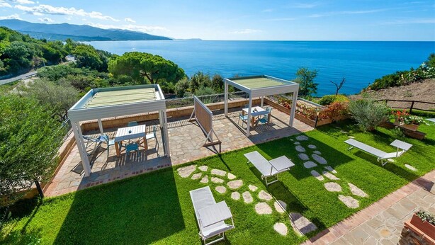 Une terrasse avec mobilier d’extérieur, une pergola et une vue sur la mer.