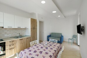 A compact living space with a kitchenette, a dining area with a table and chairs, and a seating area with a sofa and chairs.