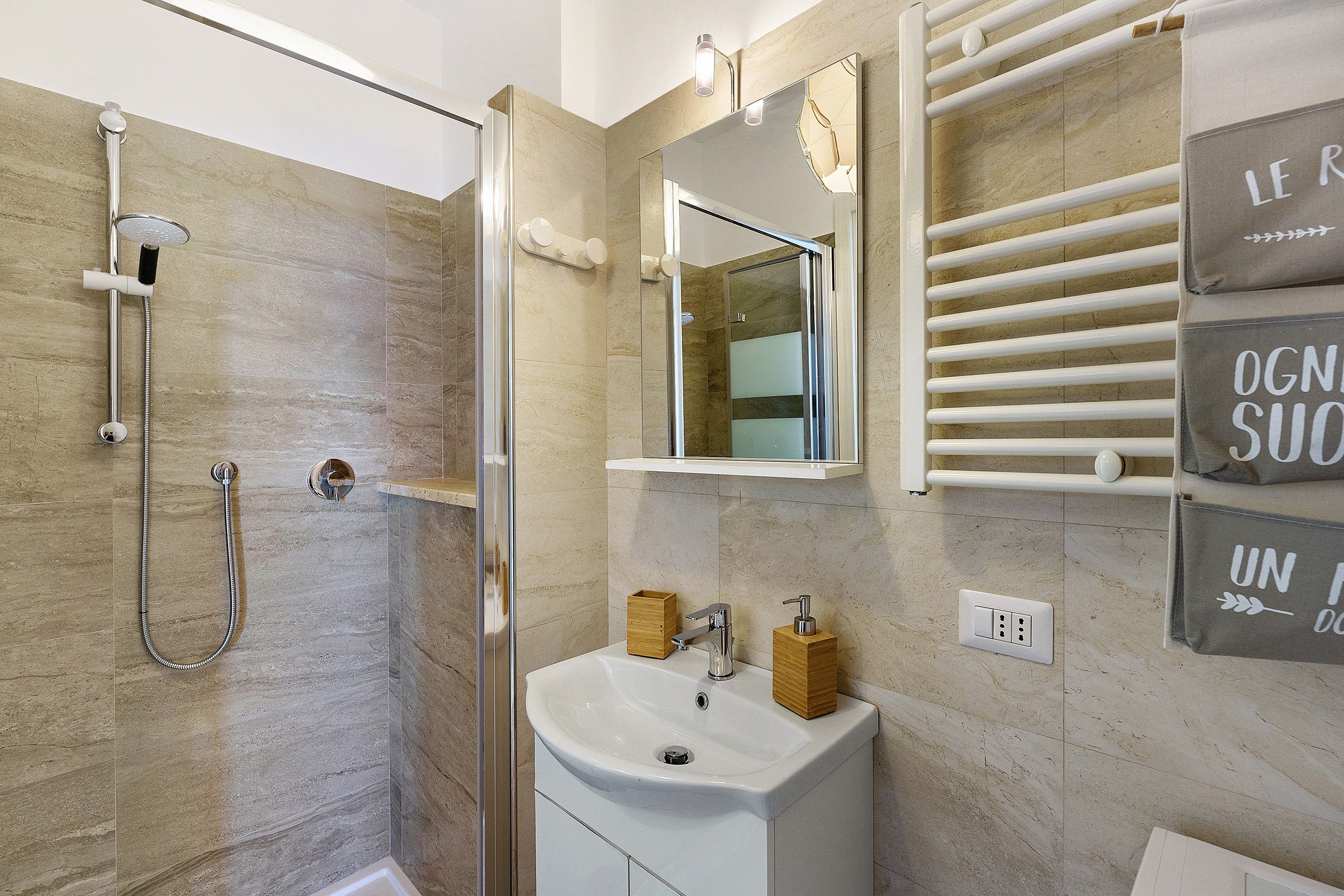 A modern bathroom with a shower, sink, and towel rack.