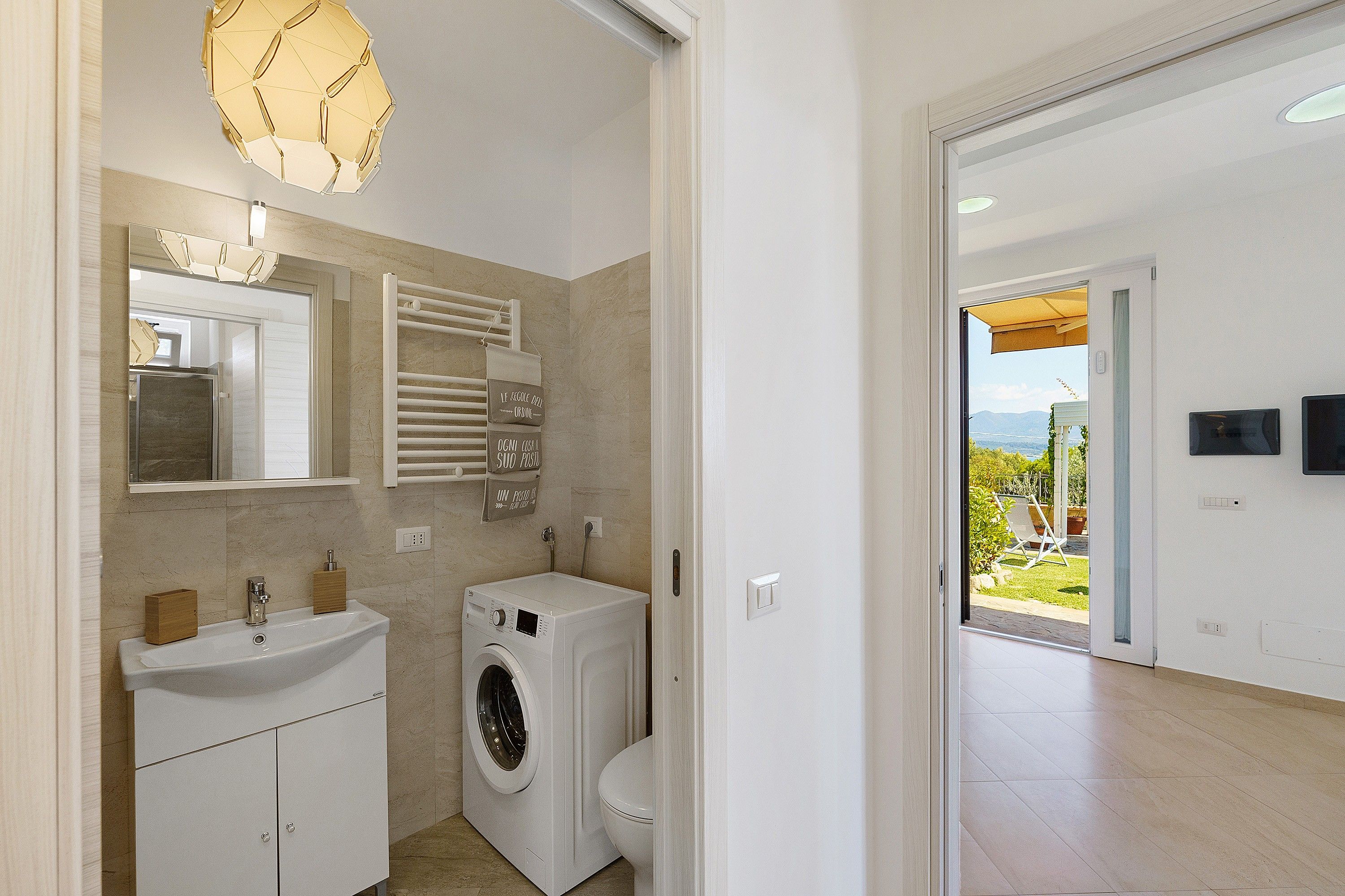Un bagno moderno con lavatrice integrata, un lavandino e un porta asciugamani.