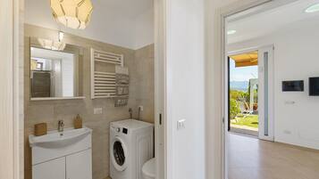 Un bagno moderno con lavatrice integrata, un lavandino e un porta asciugamani.