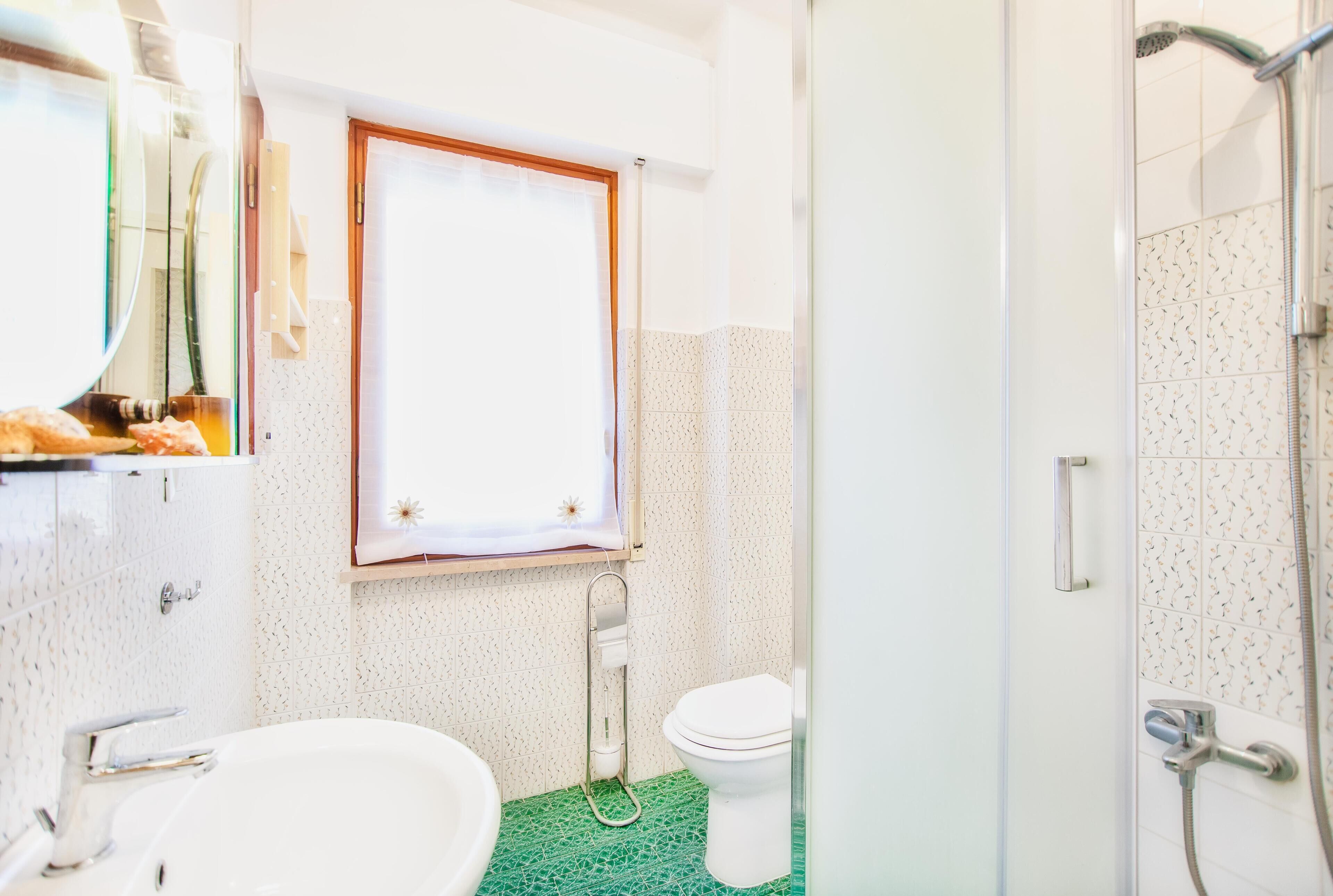 Un baño con lavamanos, inodoro y ducha blancos.