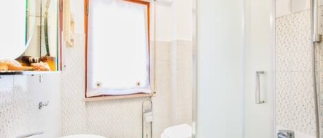 Un baño con lavamanos, inodoro y ducha blancos.