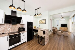 A modern kitchen with a marble countertop, black appliances, and pendant lighting. - Villa Stavroula - Two Bedroom Villa, Sleeps 4 (Mparmpati)