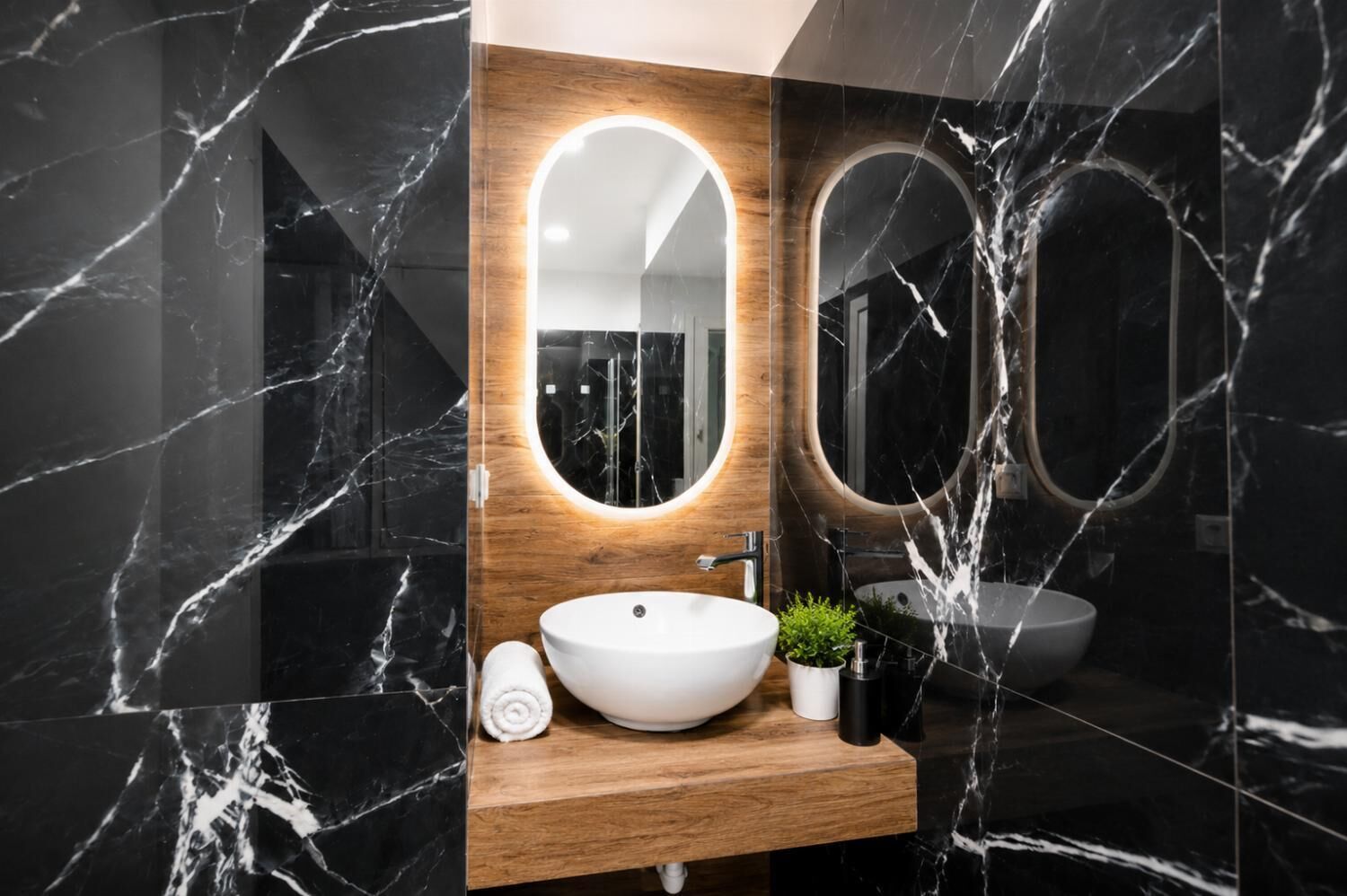 Une salle de bain moderne avec un meuble-lavabo en bois, un lavabo blanc, un miroir rond et un mur en marbre.