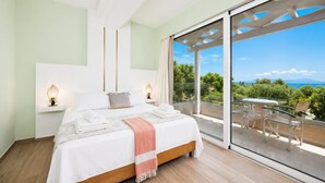 A bedroom with a large bed, bedside lamps, and a balcony with a view. - Villa Stavroula - Two Bedroom Villa, Sleeps 4 (Mparmpati)