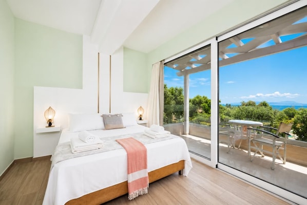 Een slaapkamer met een groot bed, nachtlampjes en een balkon met uitzicht.