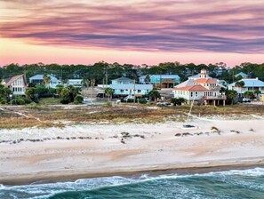 A coastal area with beachfront houses, sandy beach, and ocean waves. - Island Days: Newly Remodeled, Gorgeous Views, Private Pool, Pet Friendly, Close (St. George Island)