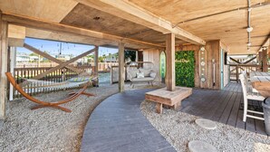 Eine Holzterrasse im Freien mit einer Hängematte, einer Sitzecke und einem Weg.