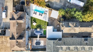 An aerial view of a residential area with a swimming pool, multiple vehicles, and surrounding buildings. - Cute and Cozy One Bedroom in Hotel with Shared Pool and Hot tub (New Orleans)