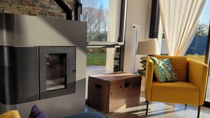 Un salon moderne avec une cheminée, un fauteuil jaune et une grande fenêtre.