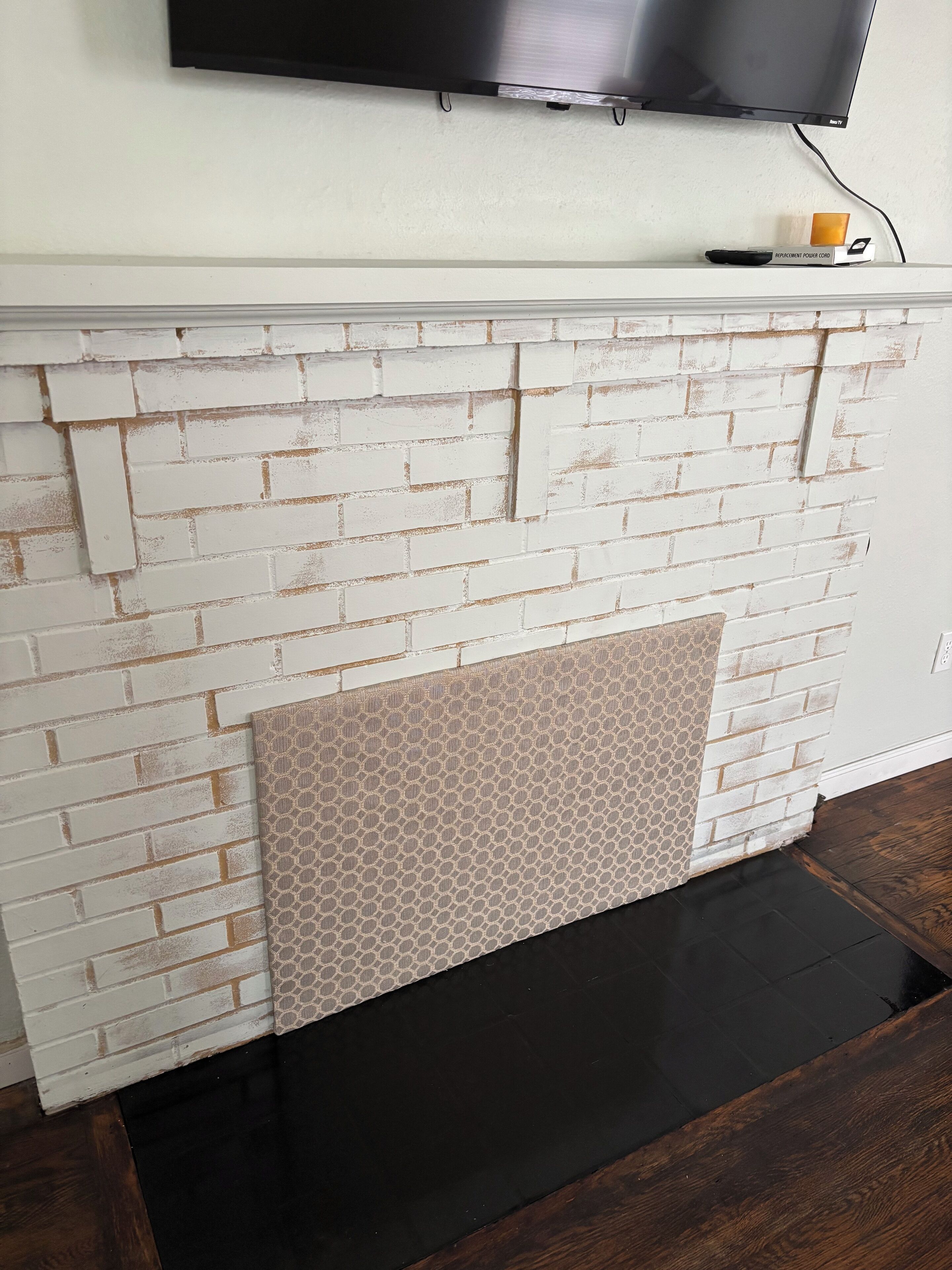 Une cheminée avec un revêtement en briques blanches et un encadrement décoré.
