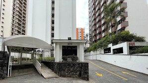 Fachada de edificio con muro de piedra, escalera cubierta y cartel que indica 'Alluga Se Vendese'.