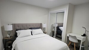 Et hotelværelse med en stor seng, et skrivebord og en stol.