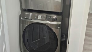 En Samsung vaskemaskine og tørretumbler, stablet i et lille vaskerum.