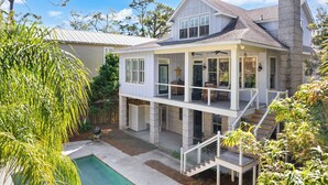 A two-story house with a covered porch, a pool, and a staircase leading to the upper level. - Hope Cottage sleeps 8 with a heated pool (St Simons Island)