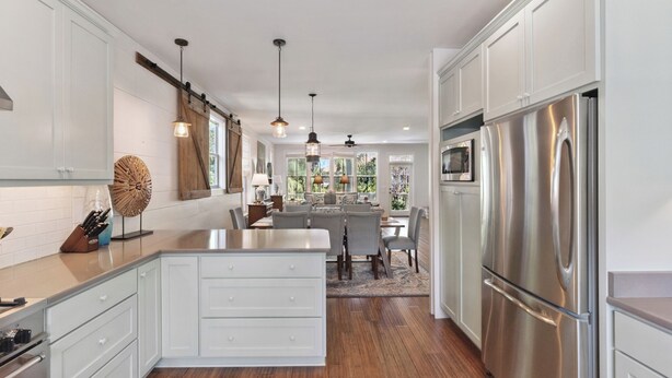 A modern kitchen with white cabinetry, stainless steel appliances, and a central island. - Hope Cottage sleeps 8 with a heated pool (St Simons Island)