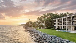 A beachfront hotel with a pool, a rocky shoreline, and a sunset view. - Ocean Front Escape sleeps 4 (St Simons Island)